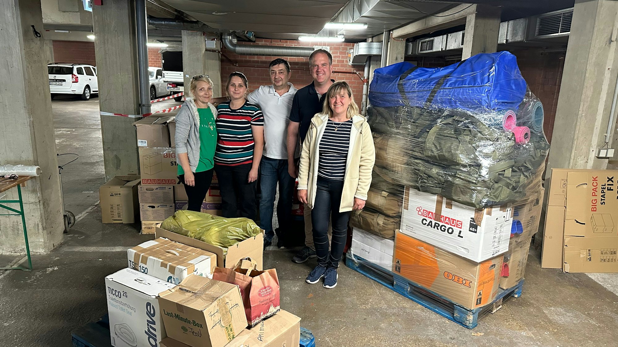 Die Helfer stehen vor den gepackten Paletten.