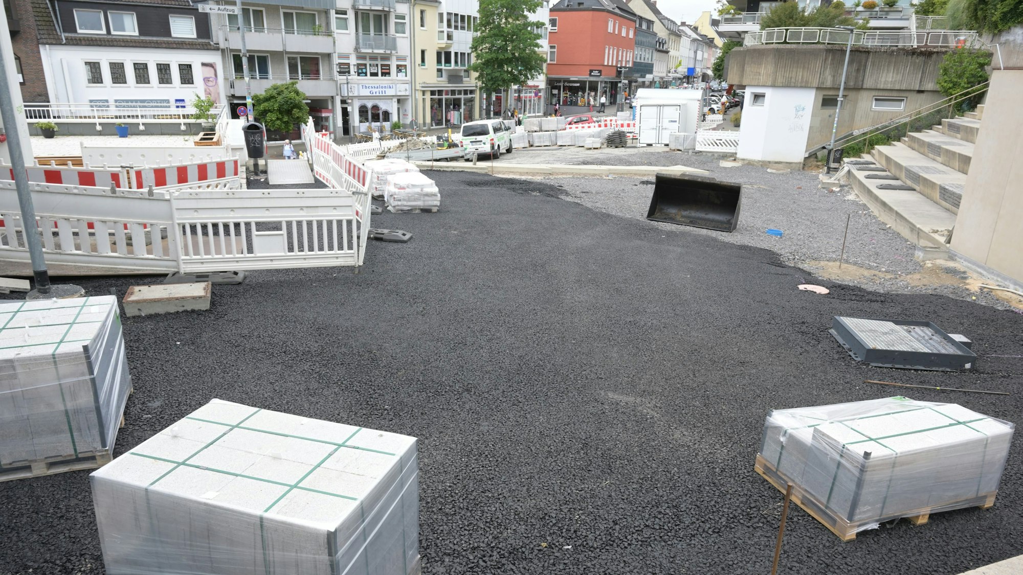 Blick von der Schlosstreppe auf den Vorplatz: Die Granitstein-Paletten stehen bereit, der Untergrund ist mit einer schwarzen Asphaltschicht vorbereitet.
