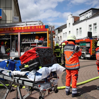 Rettungskräfte stehen vor einem Gebäude auf einer Straße.
