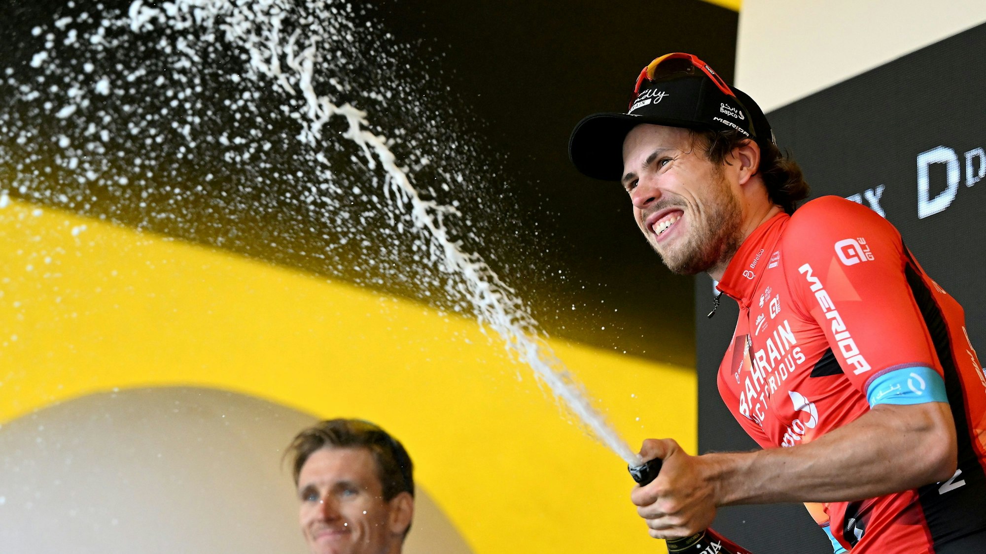 Phil Bauhaus feiert auf dem Podium mit Champagner seinen Etappensieg