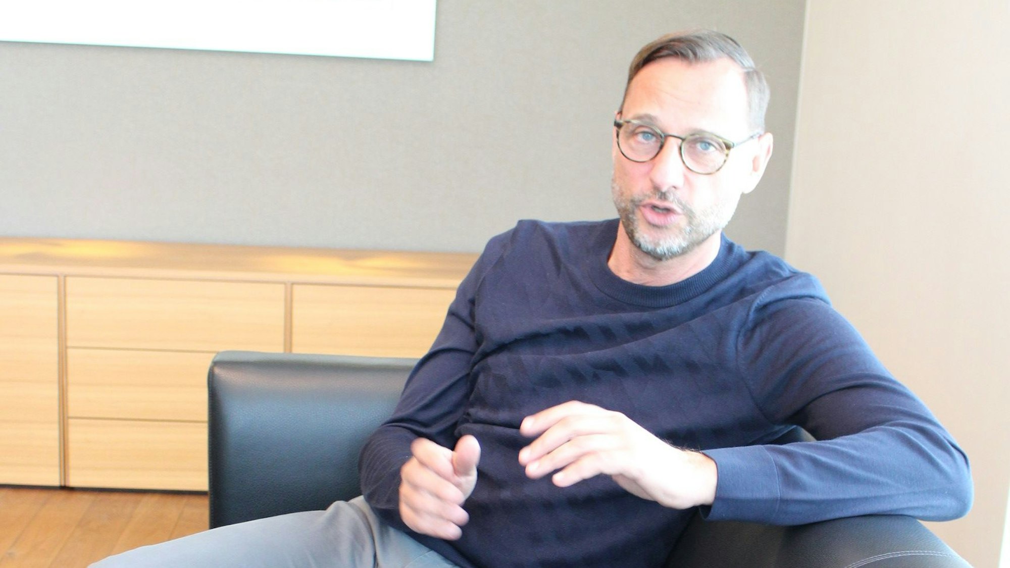 Georg Schmiedel sitzt auf einer Couch.