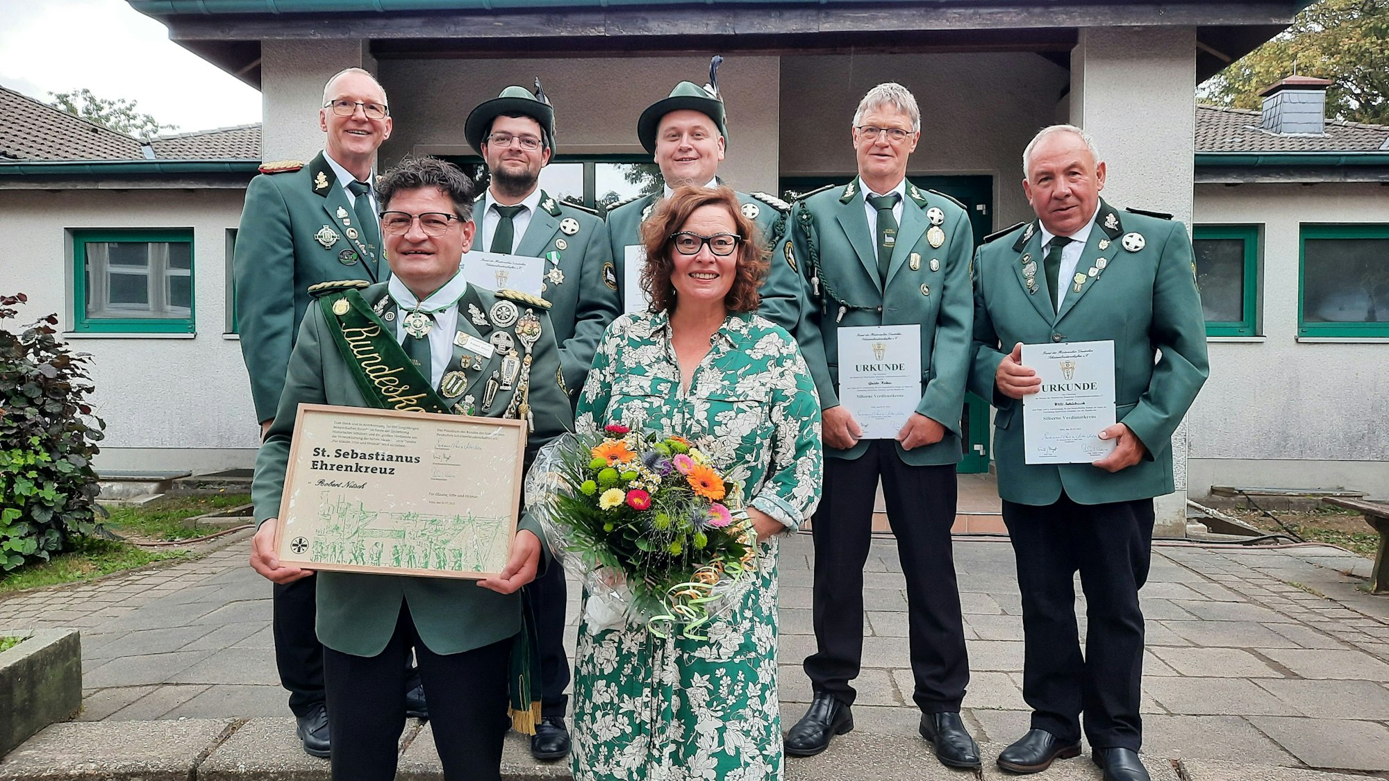 Schützen der St.-Sebastianus-Schützenbruderschaft Wipperfeld in Wipperfürth stehen nach der Ehrung in einer Gruppe vor dem Eingang der Sporthalle des Ortes.