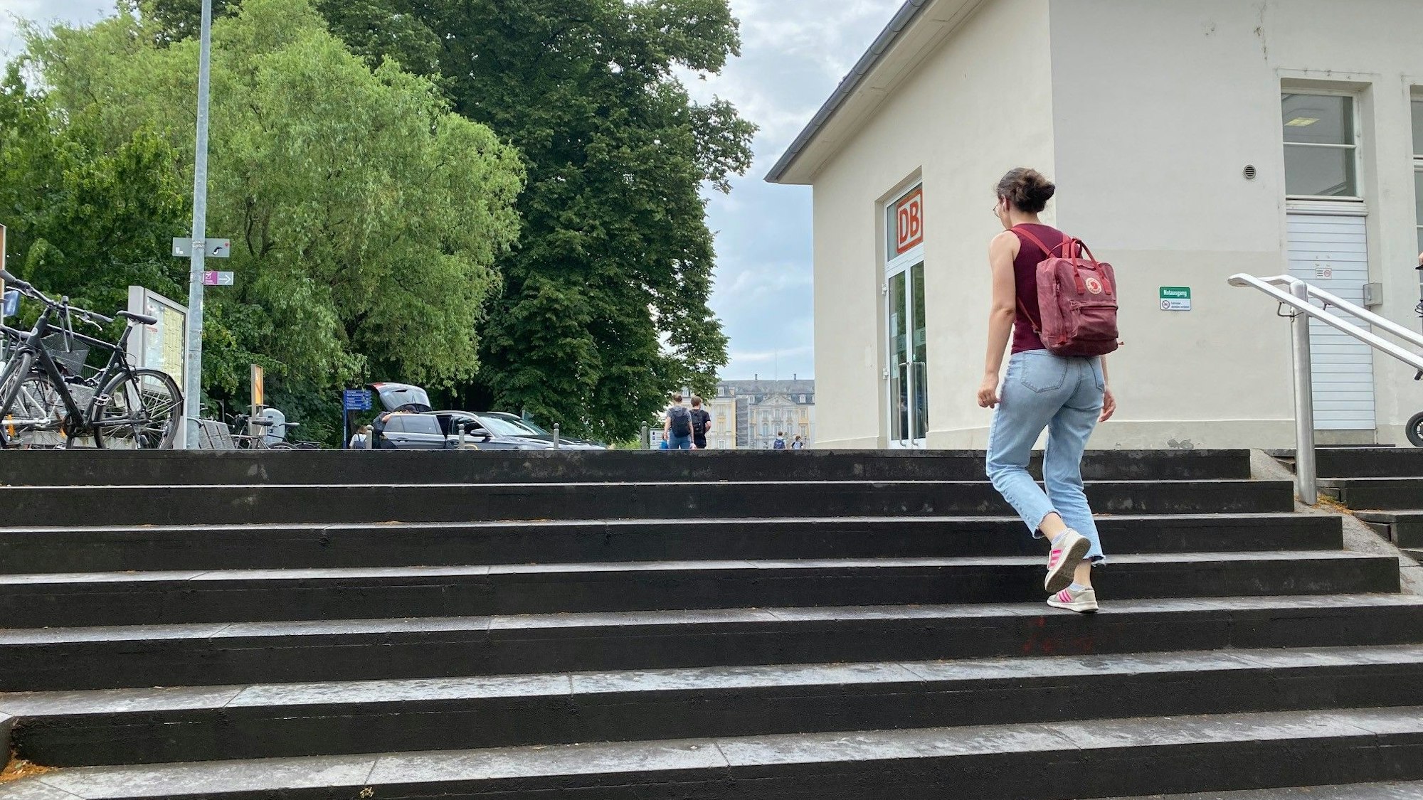 Eine Frau steigt die Treppe zum Bahnhofsvorplatz hinauf. Im Hintergrund ist das Schloss Augustusburg zu sehen.