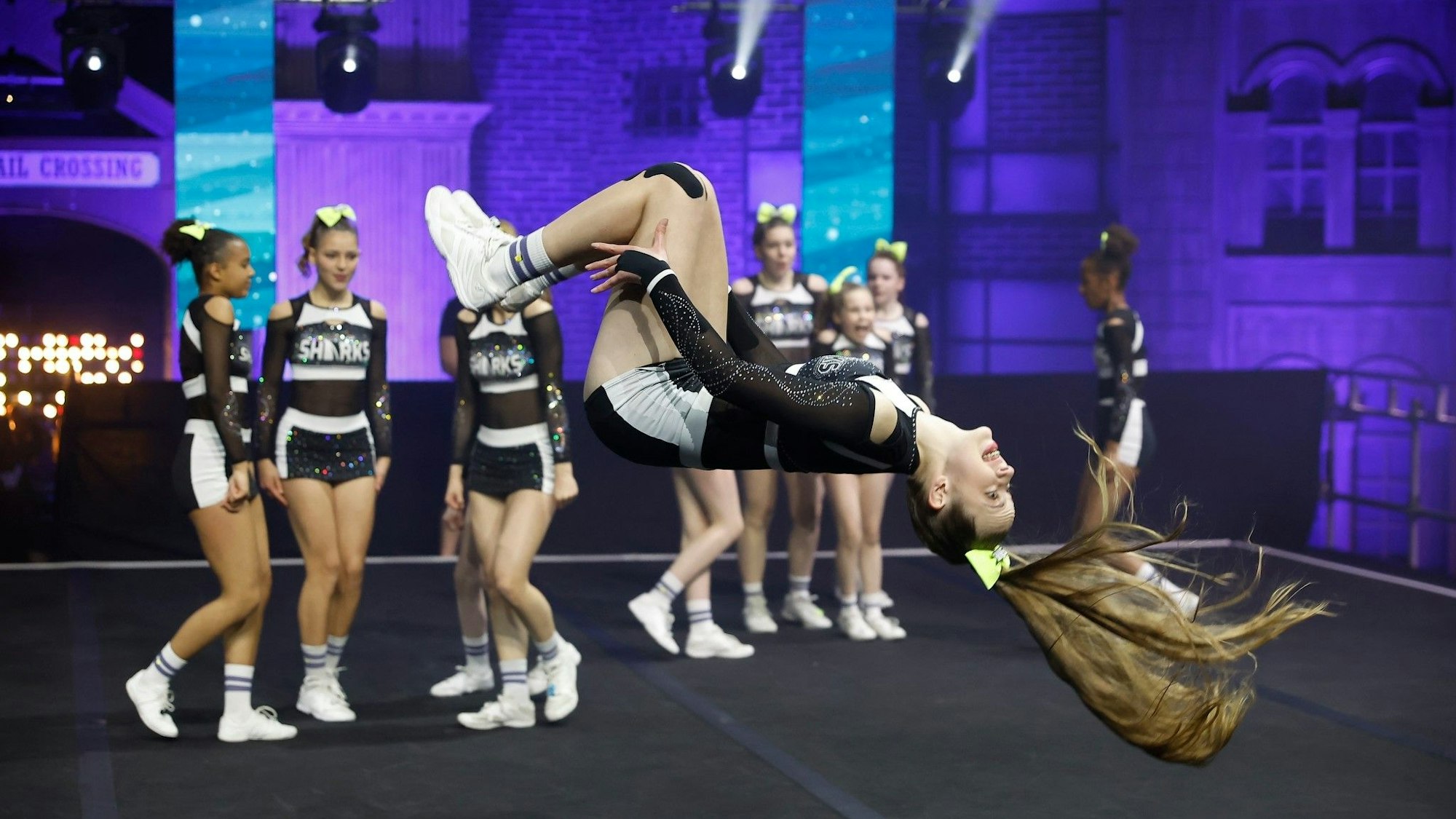 Eine Cheerleaderin macht auf der Bühne einen Rückwertssalto.