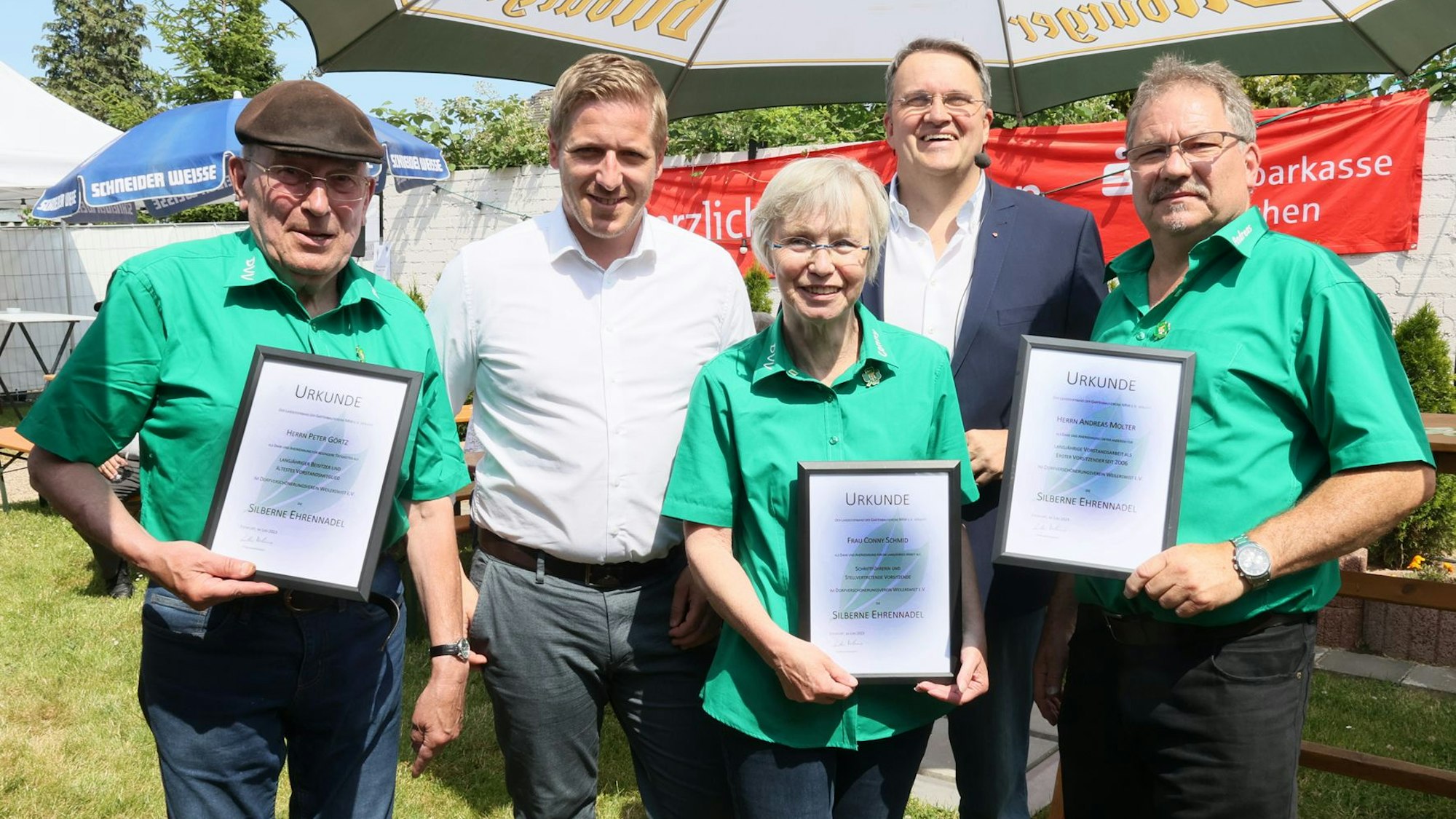 Drei Menschen in grünen T-Shirts eigen eine Urkunde.