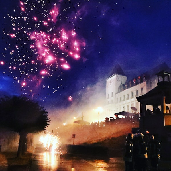 Ein Feuerwerk am Nachthimmel vor der Kulisse des Porzer Rathauses.