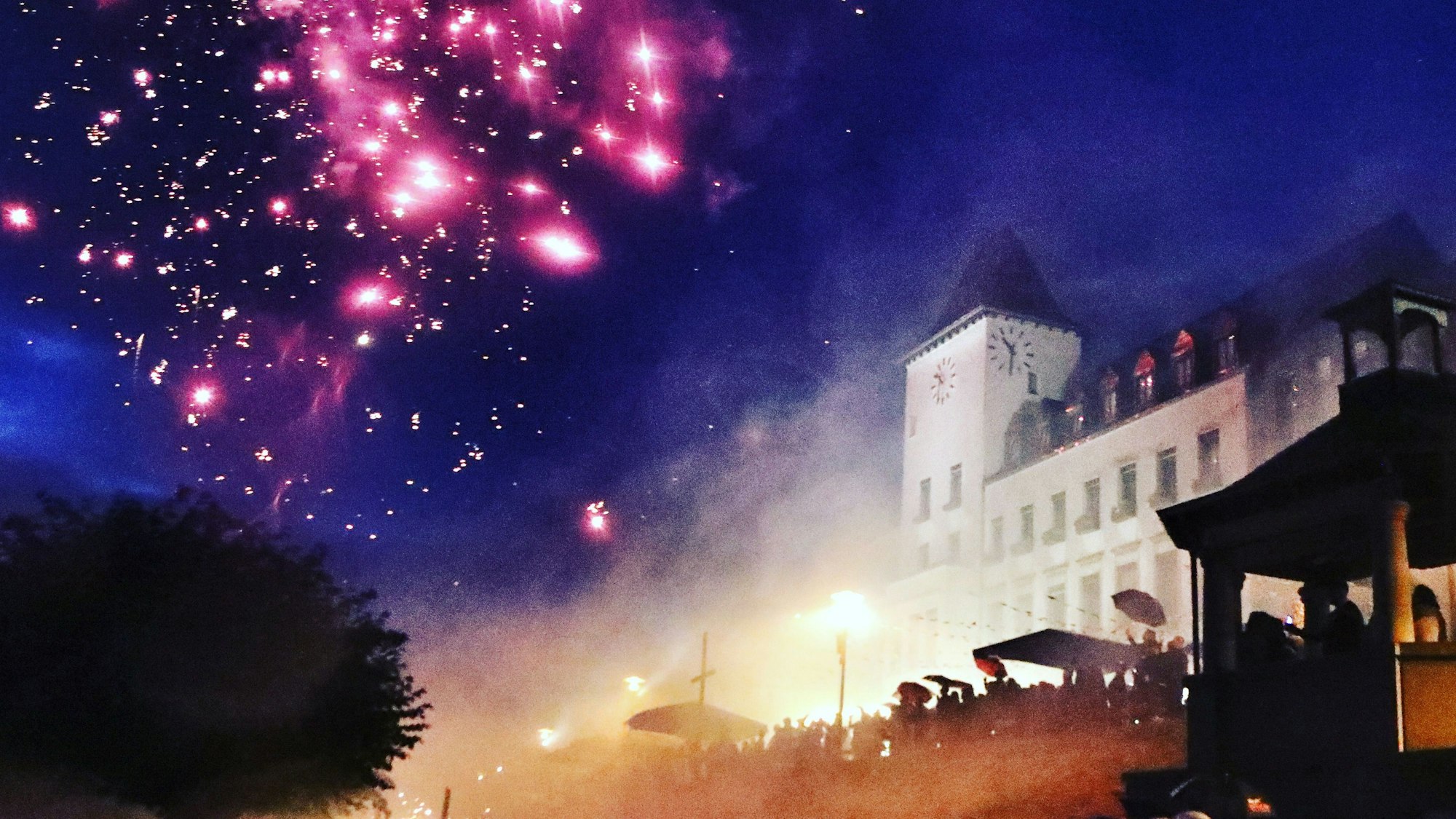 Ein Feuerwerk am Nachthimmel vor der Kulisse des Porzer Rathauses.