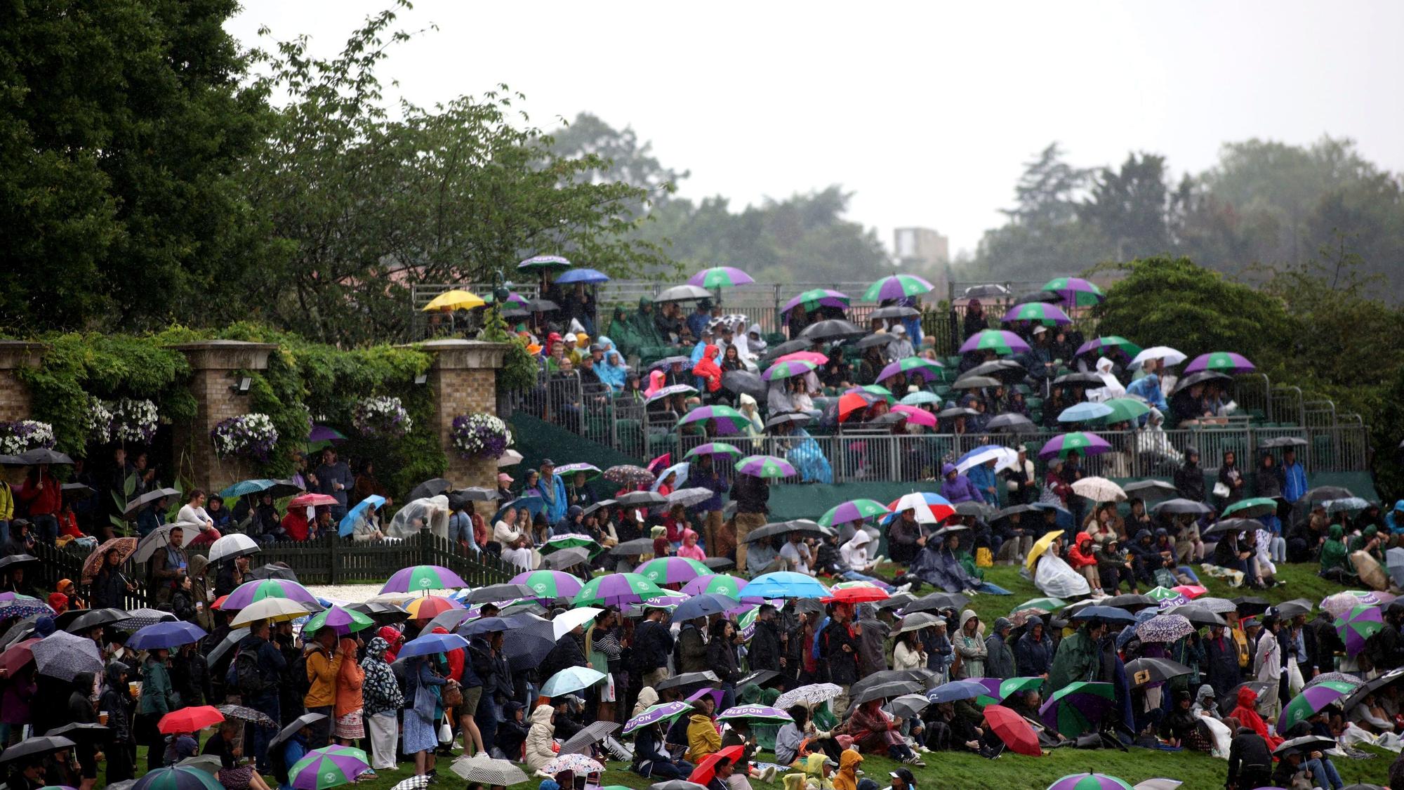 Zuschauer suchen am zweiten Tag der Tennismeisterschaften in Wimbledon Schutz vor dem Regen.