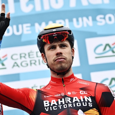 Phil Bauhaus, Rennfahrer des Radsport-Teams Bahrain-Victorious, winkt in Richtung Publikum. Er trägt das Trikot seines Teams.