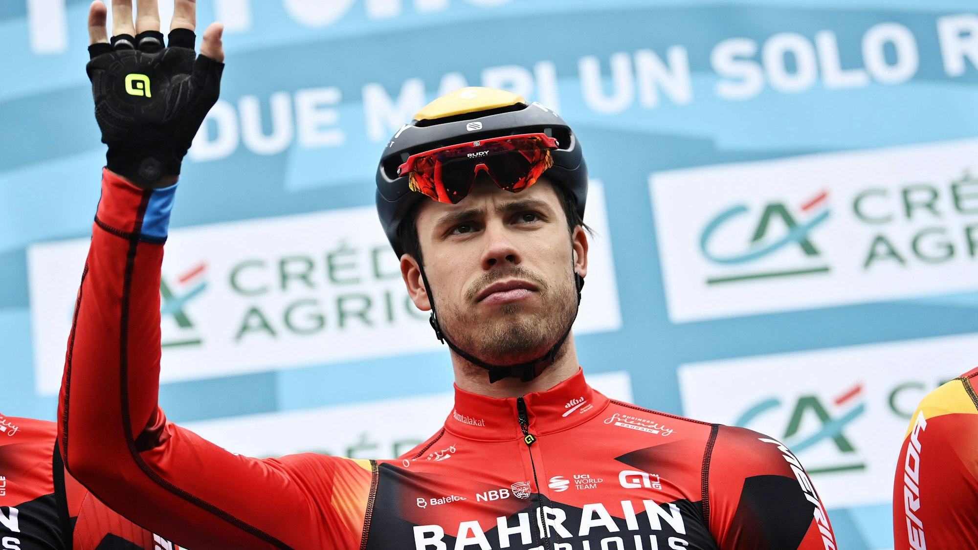 Phil Bauhaus, Rennfahrer des Radsport-Teams Bahrain-Victorious, winkt in Richtung Publikum. Er trägt das Trikot seines Teams.