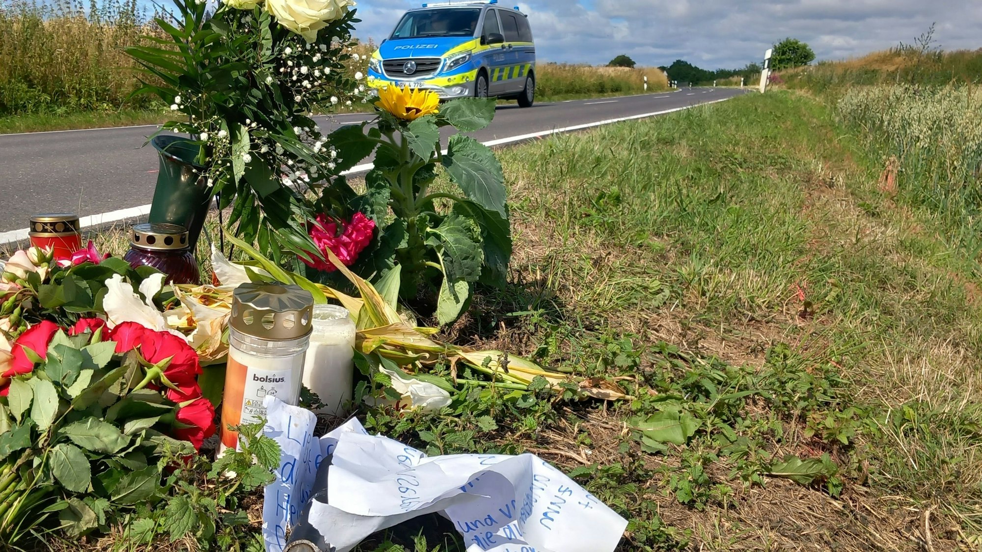 Am Ort, an dem eine 17-Jährige auf einem E-Bike nach dem Frontalzusammenstoß mit einem Auto starb, zwischen Villip und Gimmersdorf, liegen Blumen und Kerzen sowie eine Nachricht von Freunden mit einem abgebrochenen Stück Lenker.