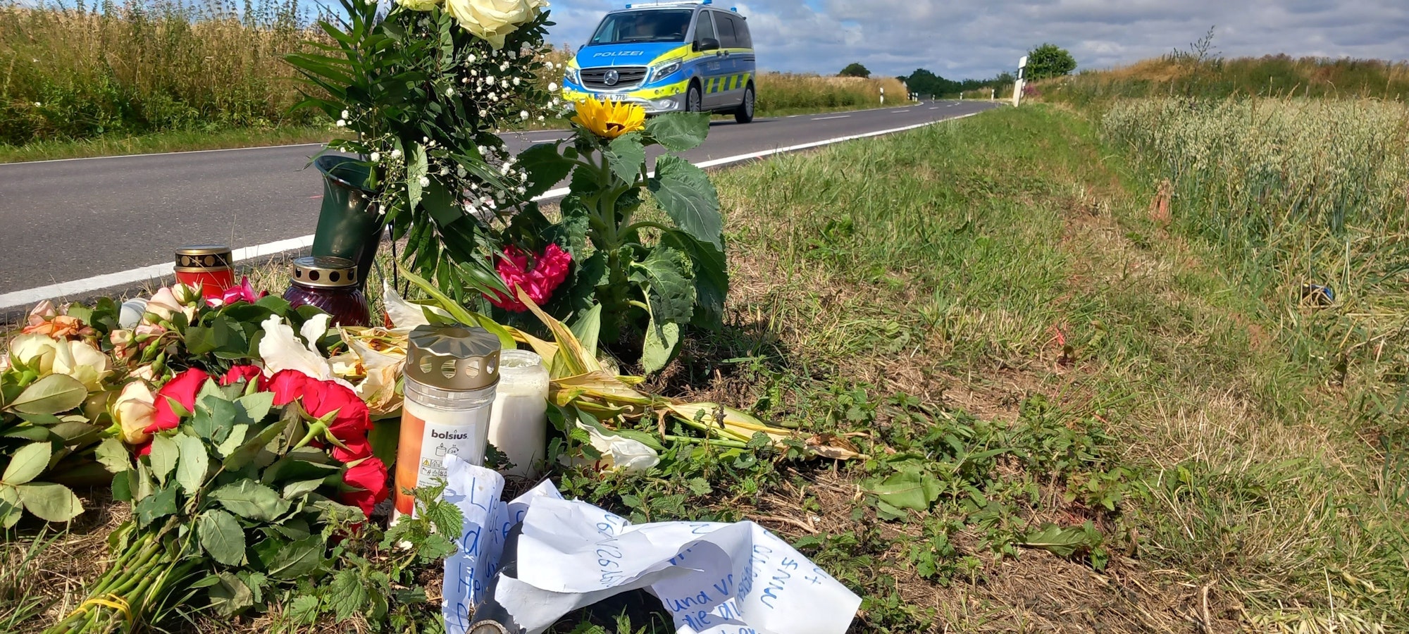 5. Juli 2023: Am Ort, an dem eine 17-Jährige auf einem E-Bike nach dem Frontalzusammenstoß mit einem Auto starb, zwischen Villip und Gimmersdorf, liegen Blumen und Kerzen sowie eine Nachricht von Freunden mit einem abgebrochenen Stück Lenker.