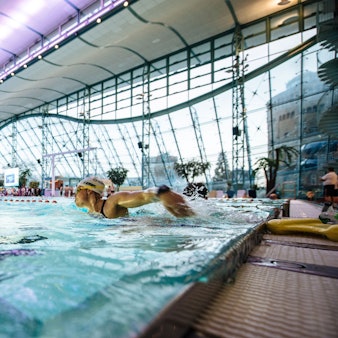 Man sieht Personen, die in einem Becken Bahnen schwimmen.