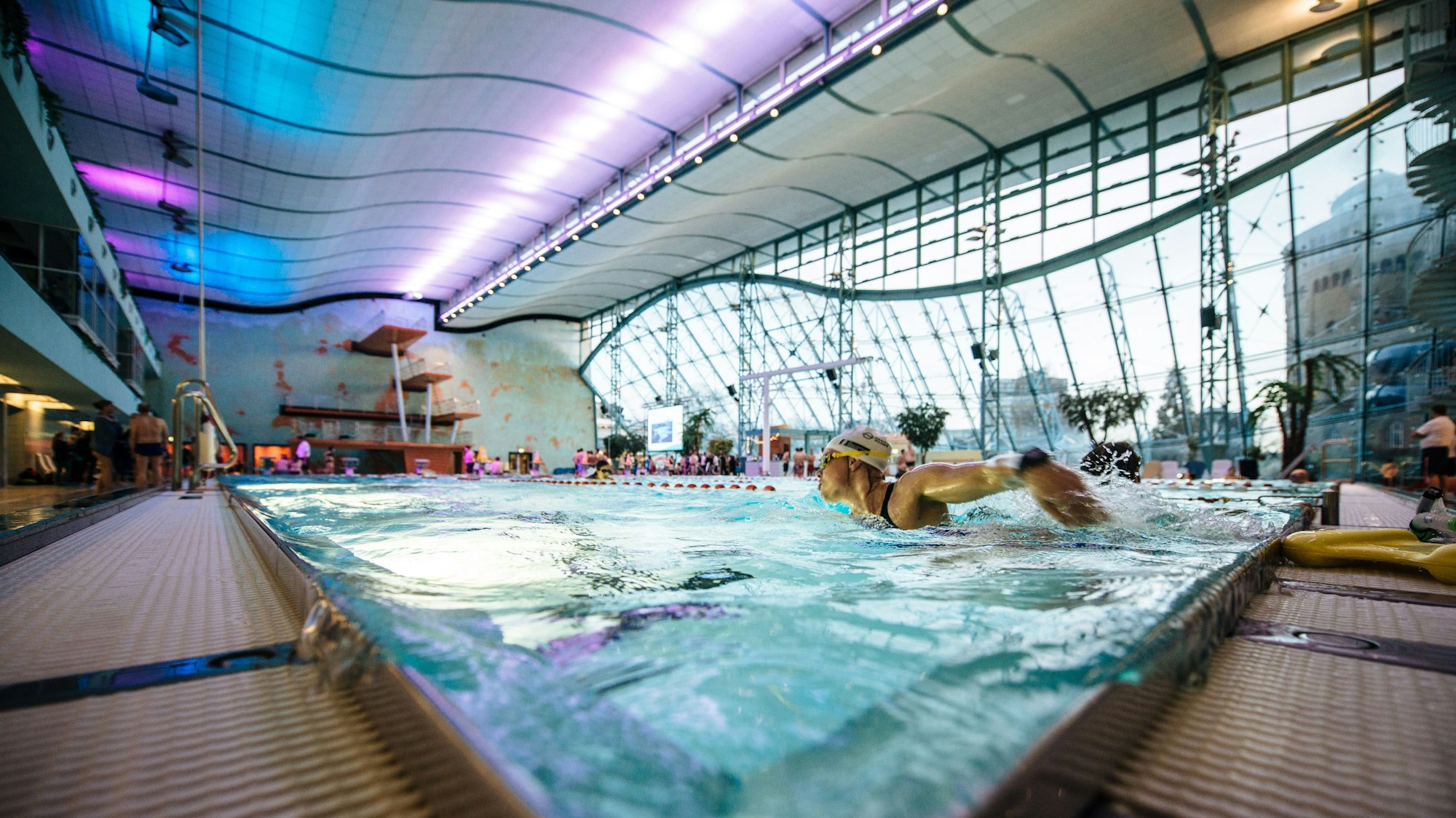 Man sieht Personen, die in einem Becken Bahnen schwimmen.