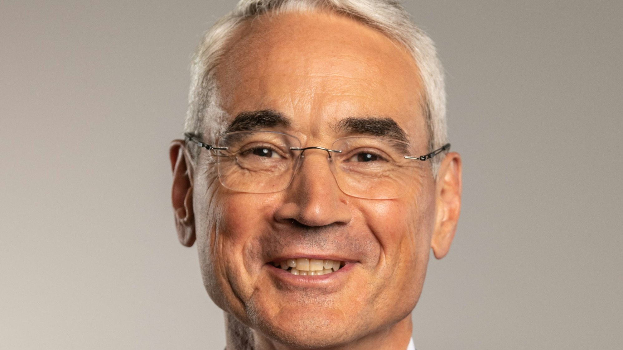 Ein Portätfoto von Wolfgang Mödder. Er hat hellgraues kurzes Haar, guckt freundlich und trägt eine rahmenlose Brille.