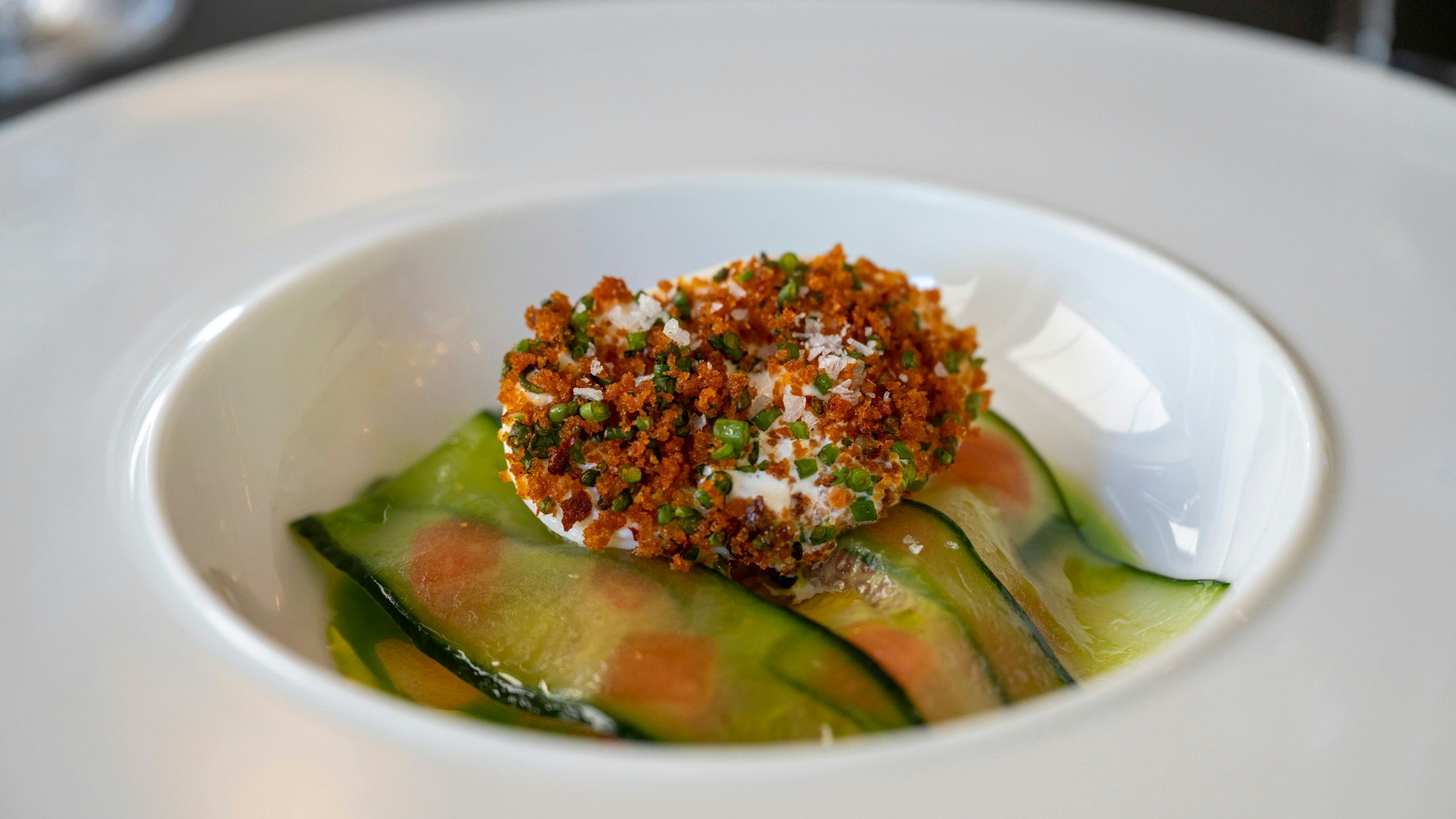 Burrata, Gurke, Melone und Rettich mit Holunderblüten-Vinaigrette liegen auf einem Teller.