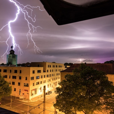 Hinter dem Kirchturm der Kirche "Zur heiligen Familie“i n Köln schlägt ein Blitz ein.