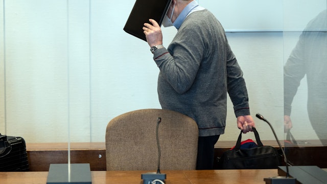 Der angeklagte katholische Priester hält sich im Gerichtssaal eine Mappe vor das Gesicht.