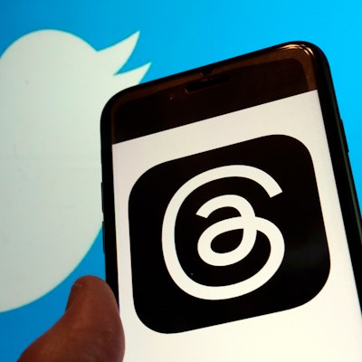 Blick auf das Logo für Metas neue App Threads auf einem Handy-Display und das Logo von Twitter.