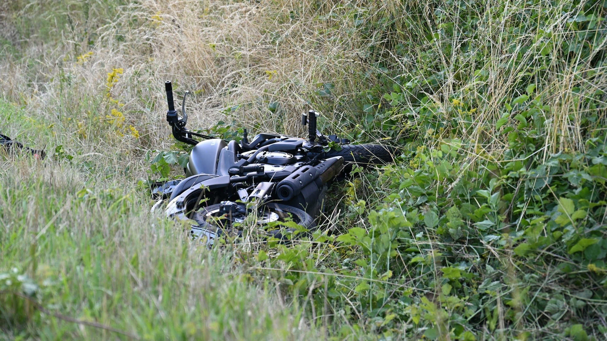 Ein Motorrad liegt nach einem Unfall in einem Seitengraben.