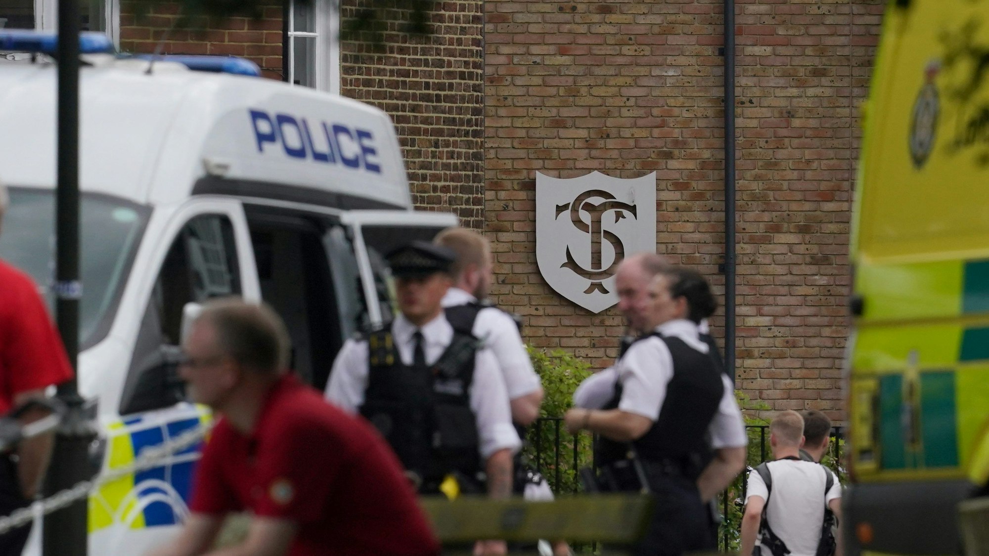 06.07.2023, Großbritannien, London: Polizisten treffen am Einsatzort ein, nachdem mehrere Menschen im Stadtteil Wimbledon verletzt worden, als ein Auto gegen das Gebäude einer Grundschule gefahren ist.