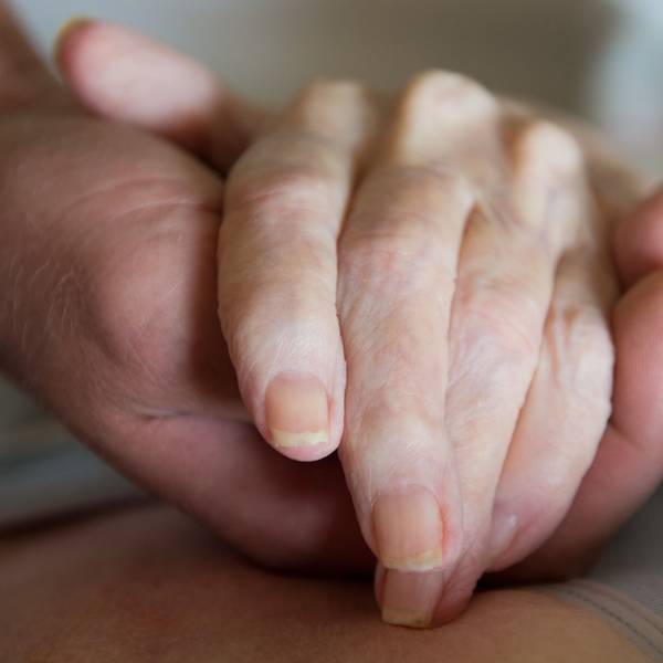 Ein Altenpfleger hält in einem Pflegeheim die Hand einer Frau. (Symbolbild)