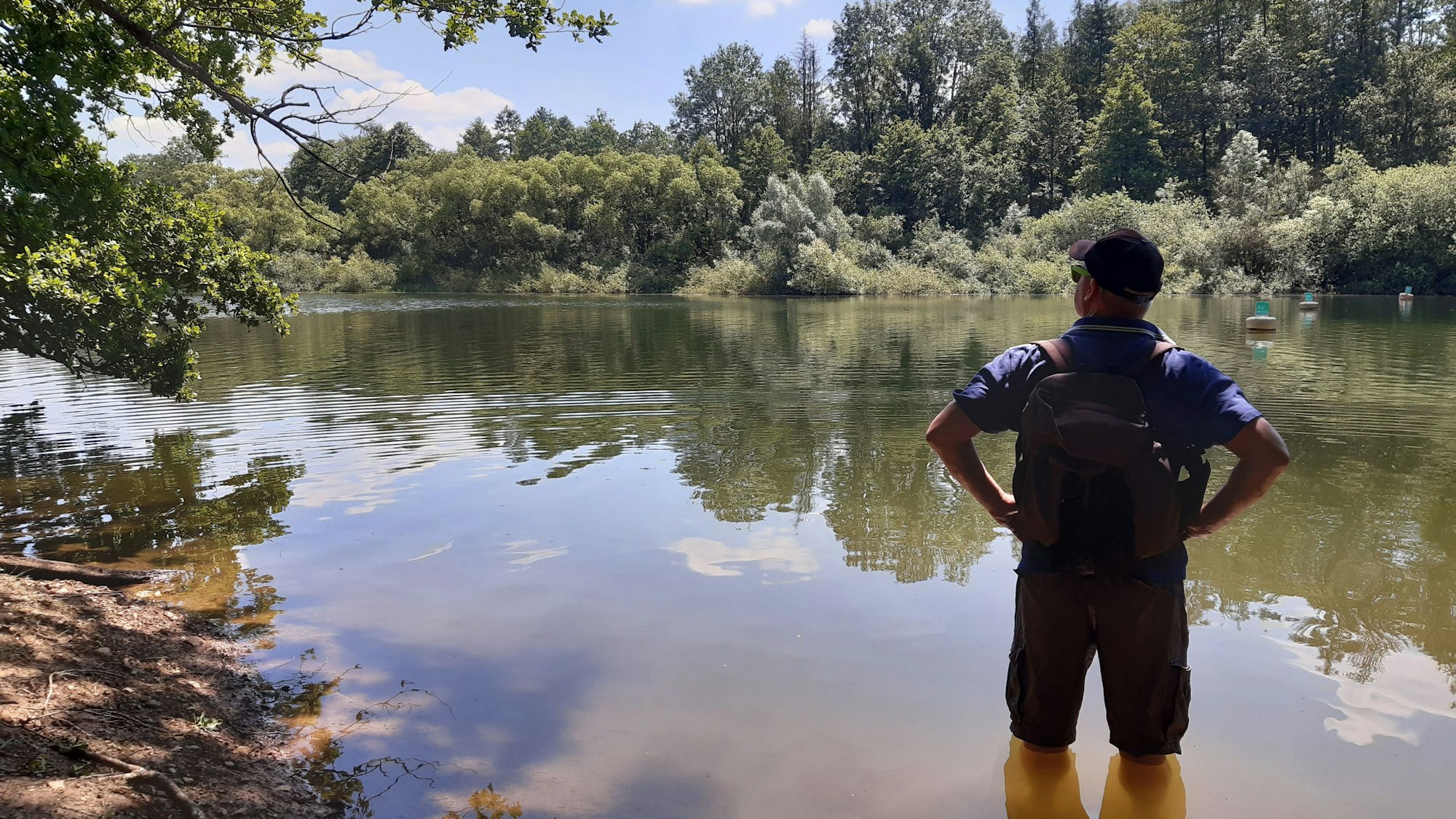 Ein Wanderer steht bis zu den Knien im Wasser.