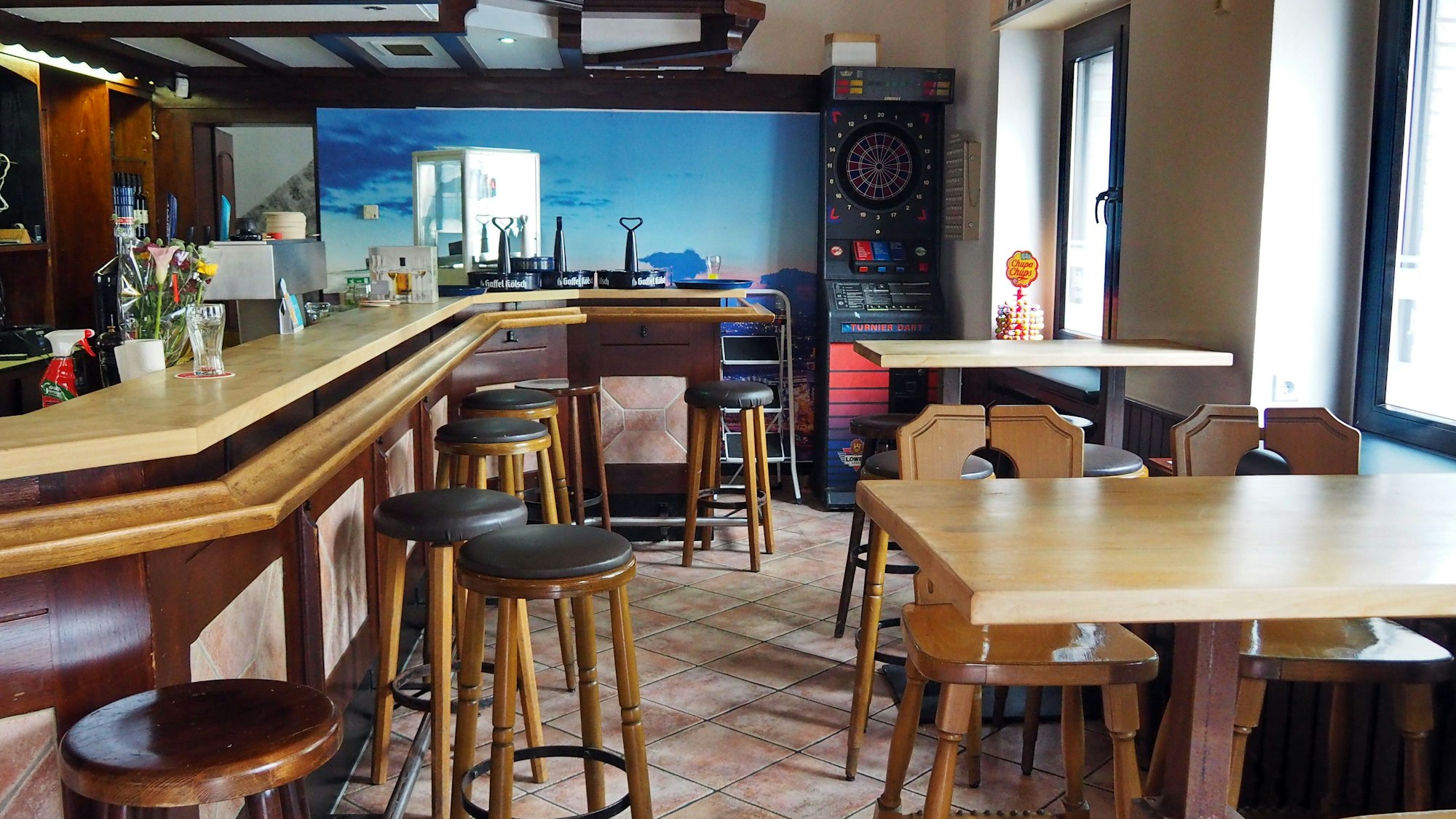 Gefliester Boden, eine Theke, mit Barhockern, Tische mit Hochstühlen und ein Darts-Automat: So sieht der Innenraum der Gaststätte Mehl aus.