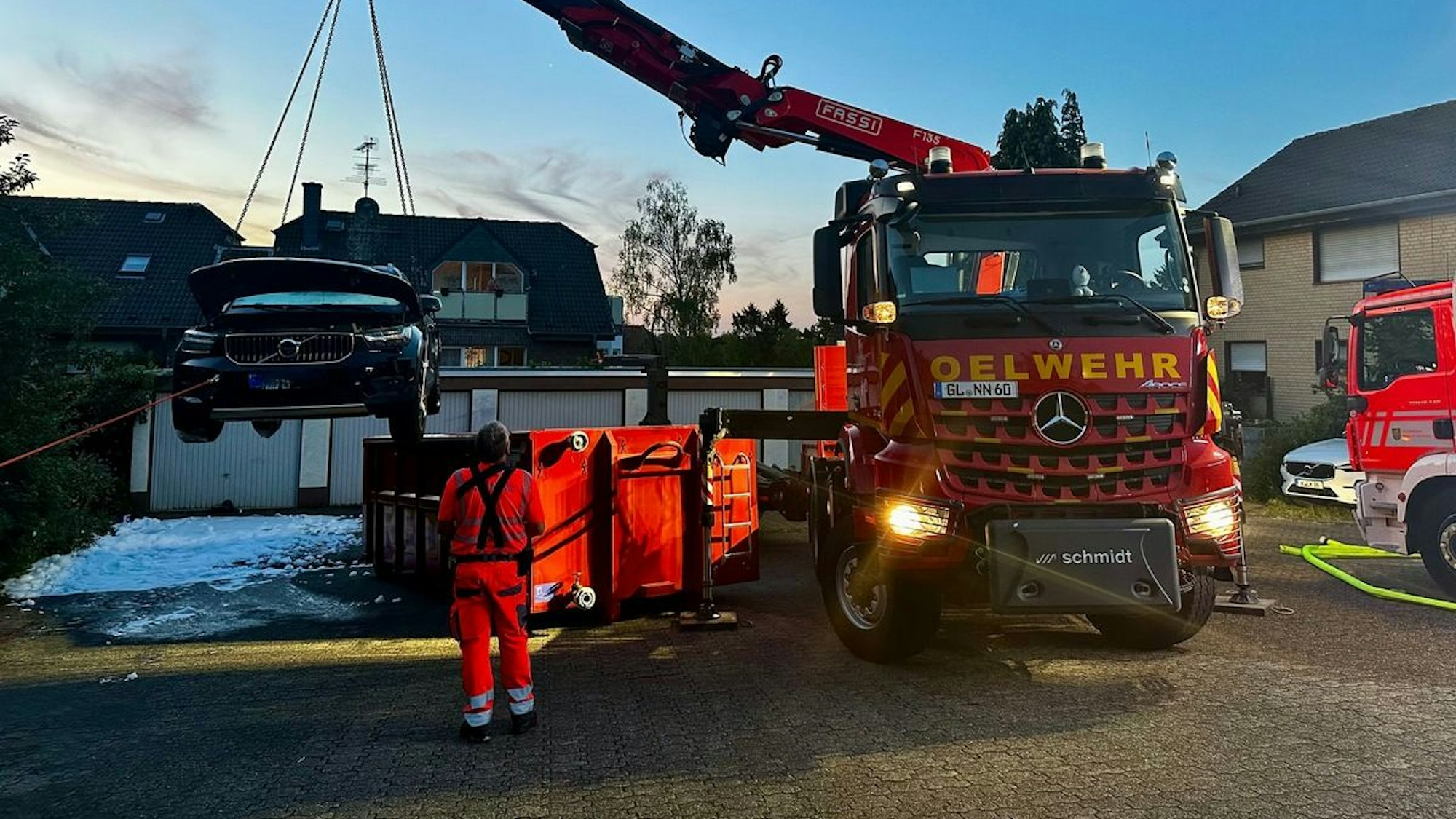 An einem Kran hängt das ausgebrannte E-Auto.