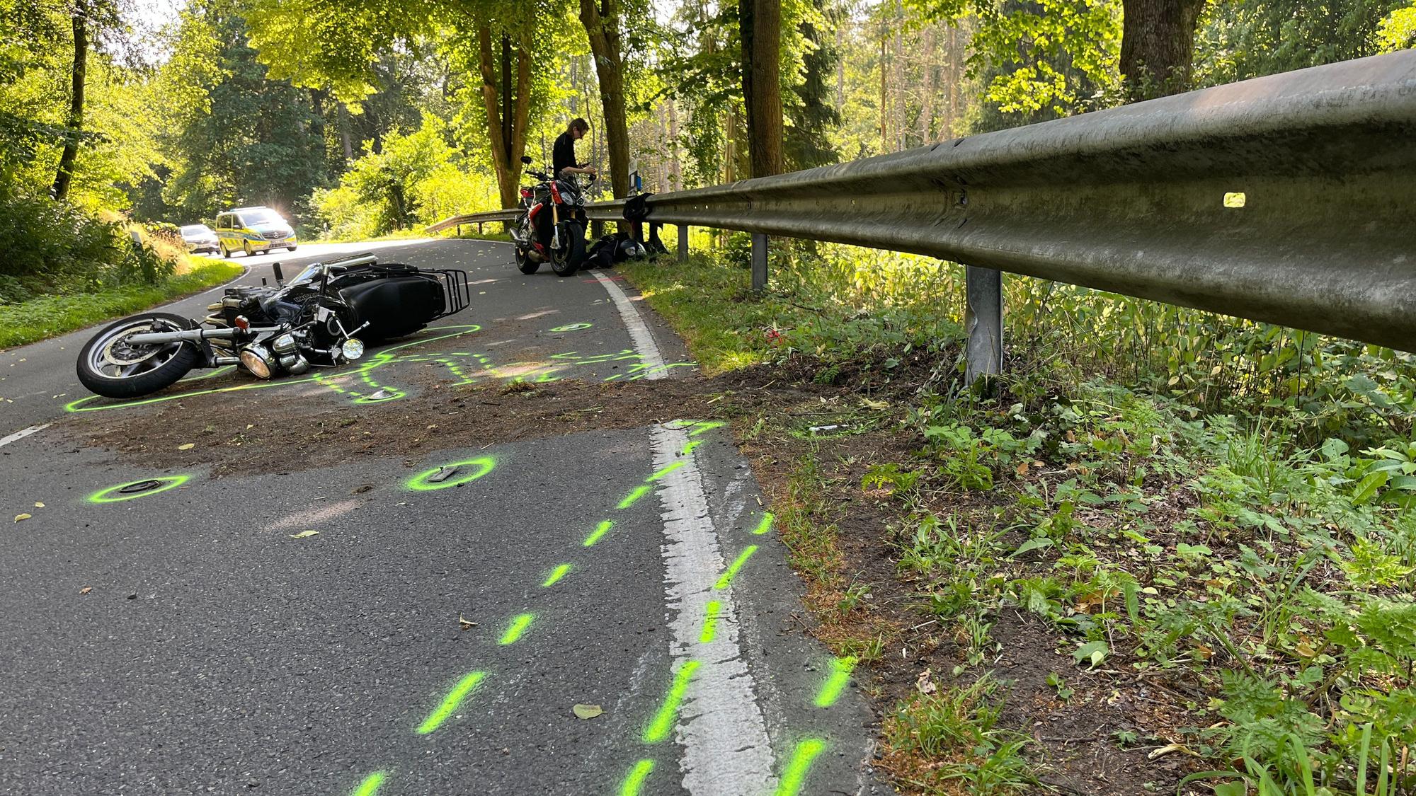Ein Motorrad liegt nach einem Zusammenstoß auf dem Boden. Vor dem Zweirad wurden von der Polizei Unfallmarkierungen auf den Boden gesprüht.