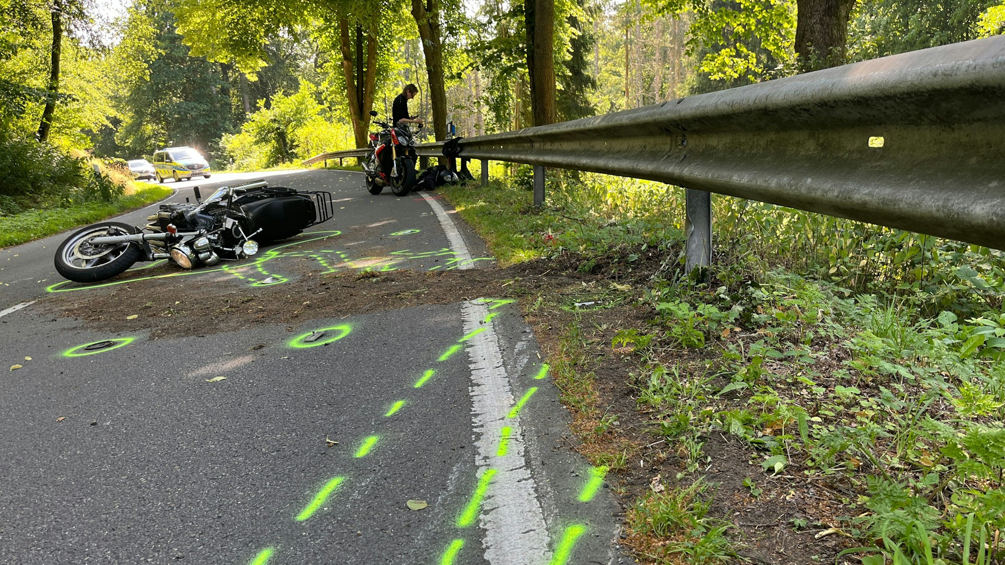 Ein Motorrad liegt nach einem Zusammenstoß auf dem Boden. Vor dem Zweirad wurden von der Polizei Unfallmarkierungen auf den Boden gesprüht.