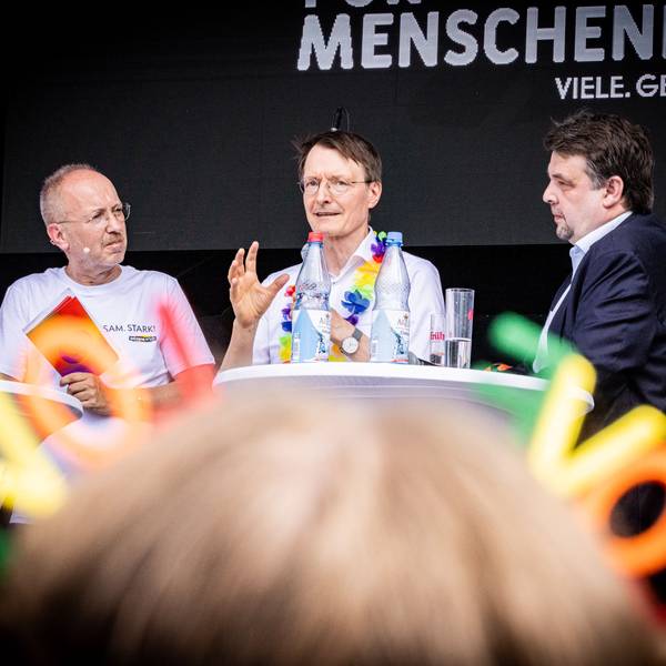 Männer diskutieren auf einer Bühne.