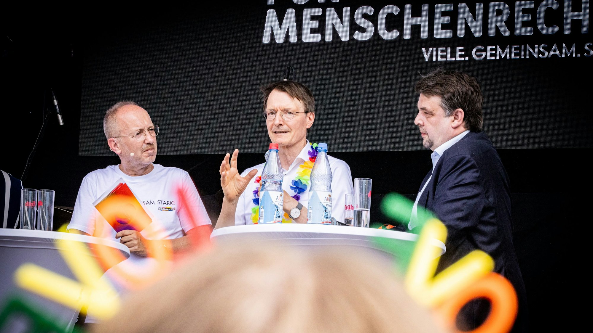 Männer diskutieren auf einer Bühne.