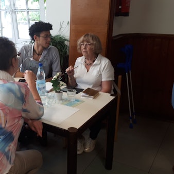 Ein junger Mann sitzt mit drei älteren Damen an einem Tisch.