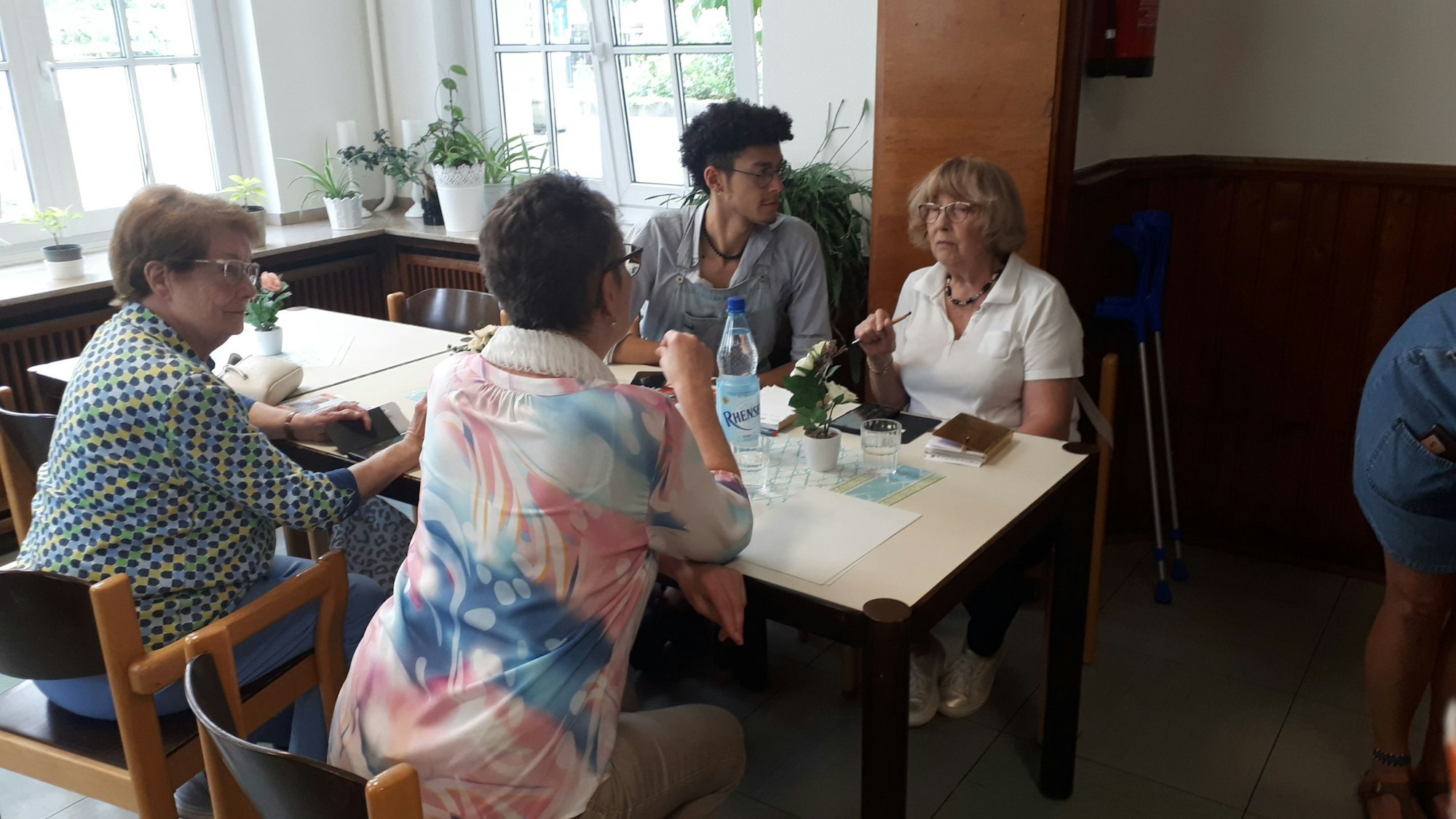 Ein junger Mann sitzt mit drei älteren Damen an einem Tisch.