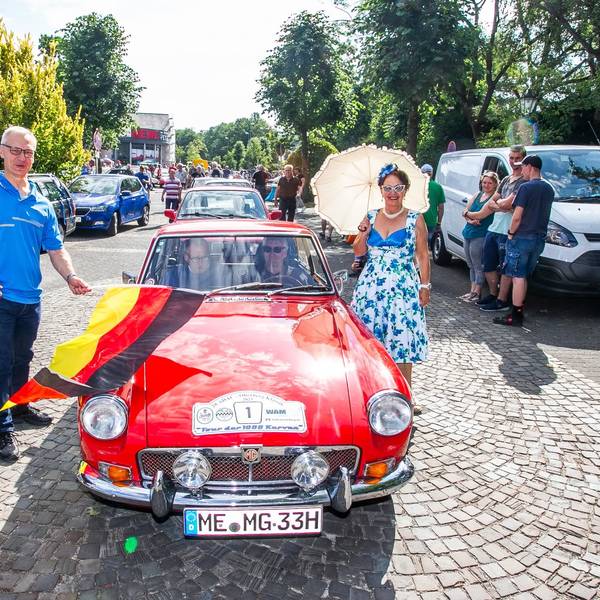 Lindlars Bürgermeister schwenkt die Startflagge bei der Abfahrt zur ADAC-Oldtimer-Rallye.