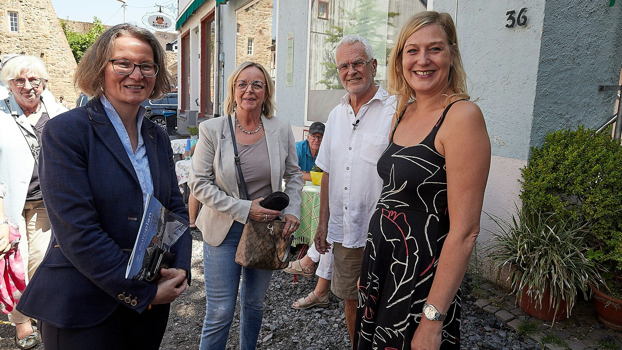 Ministerin Ina Scharrenbach (l.) und Bürgermeisterin Sabine Preiser-Marian (2.v.l.) sprechen mit Marcel Hayen und Melanie Dederichs, deren Geschäfte in Bad Münstereifel bei der Flutkatastrophe 2021 zerstört worden waren.