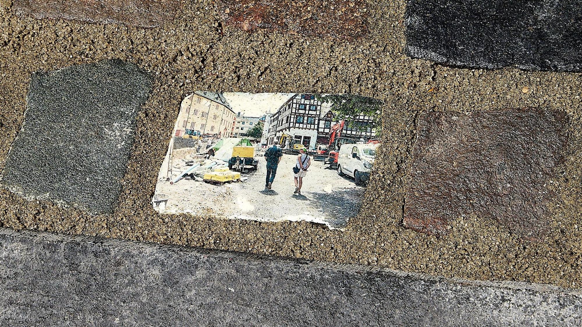 Das Bild zeigt mehrere einbetonierte Steine. Auf einem ist ein Motiv aus den Tagen nach der Flutkatastrophe in Bad Münstereifel aufgedruckt.
