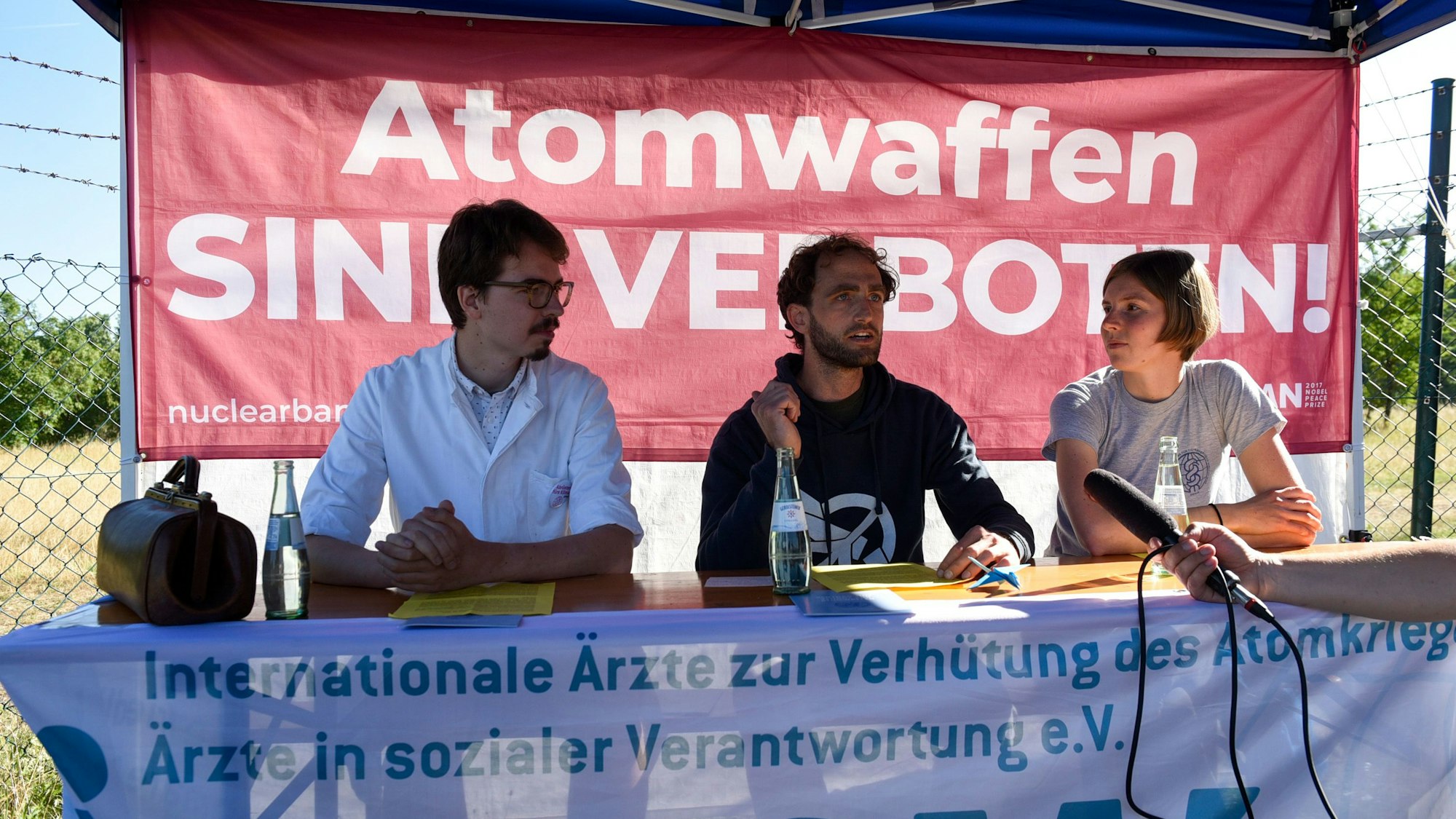 Vor dem Fliegerhorst in Nörvenich informieren Ärzte bei einem improvisierten Pressegespräch im Freien über die Gefahren, die von Atomwaffen ausgehen.