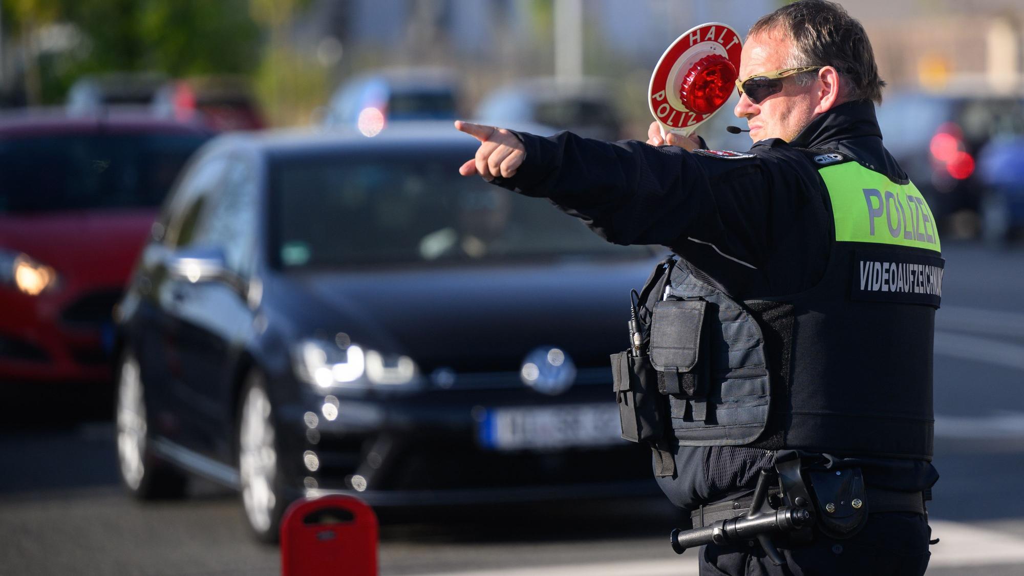 Ein Polizist winkt Autofahrer zu einer Kontrolle raus.