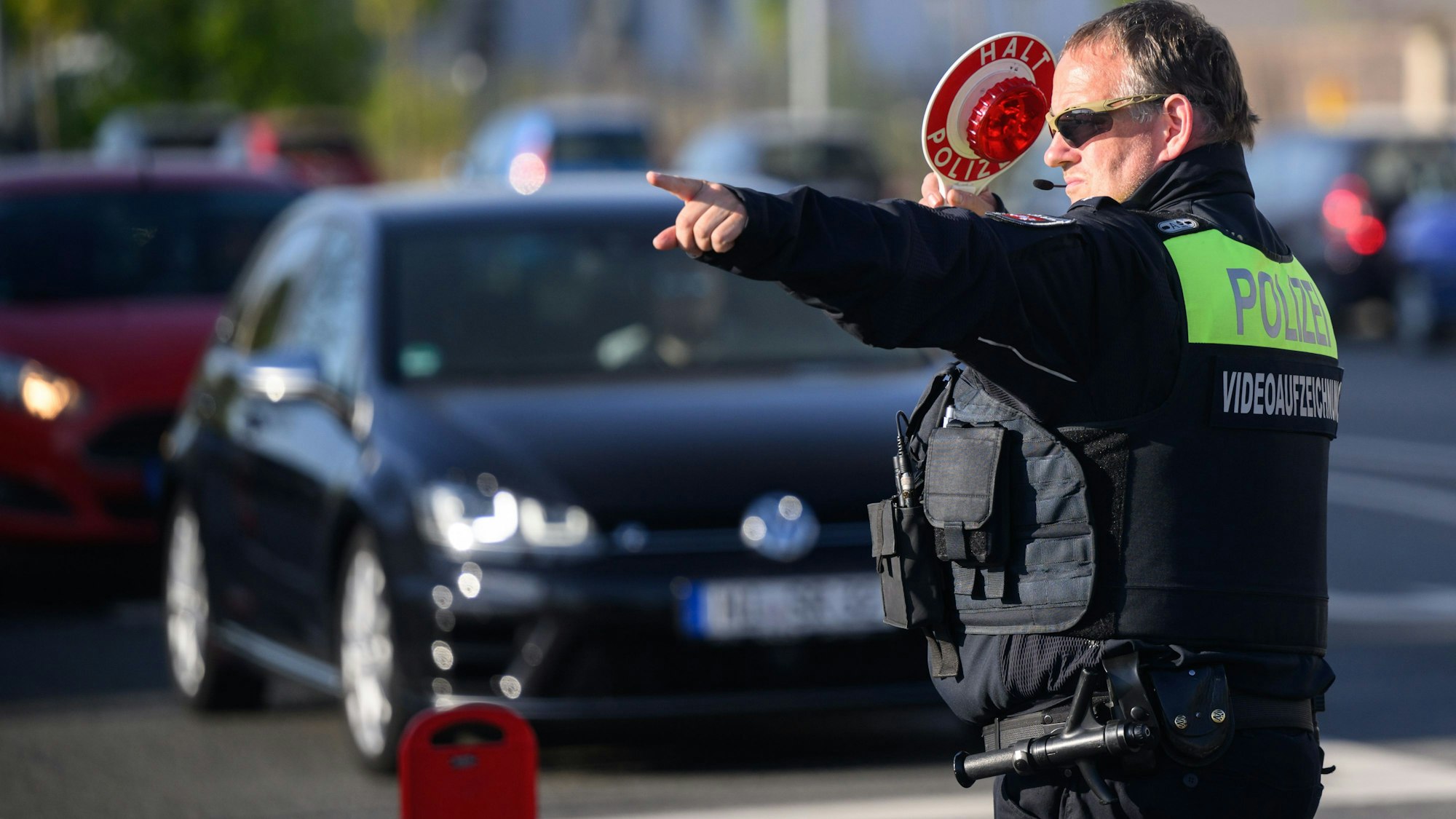Ein Polizist winkt Autofahrer zu einer Kontrolle raus.