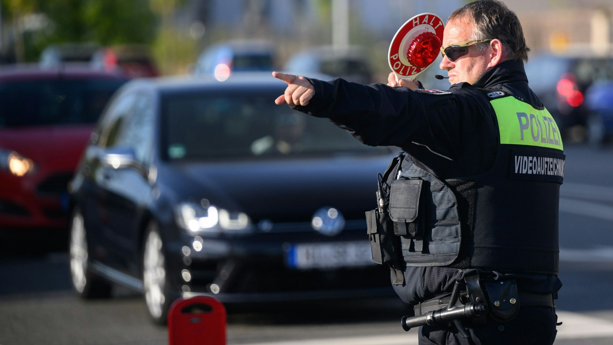 Ein Polizist der Polizei winkt Autofahrer zu einer Kontrolle raus.
