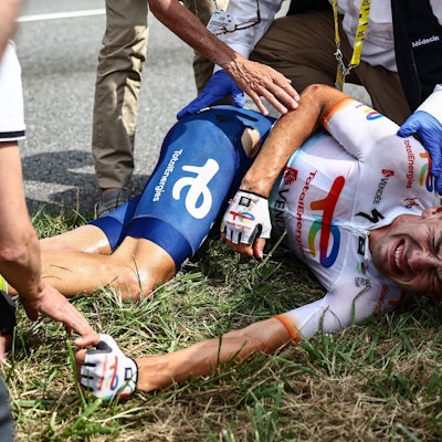 Steff Cras (M) aus Belgien vom Team TotalEnergies reagiert nach seinem Sturz auf der Strecke mit schmerzverzerrtem Gesicht