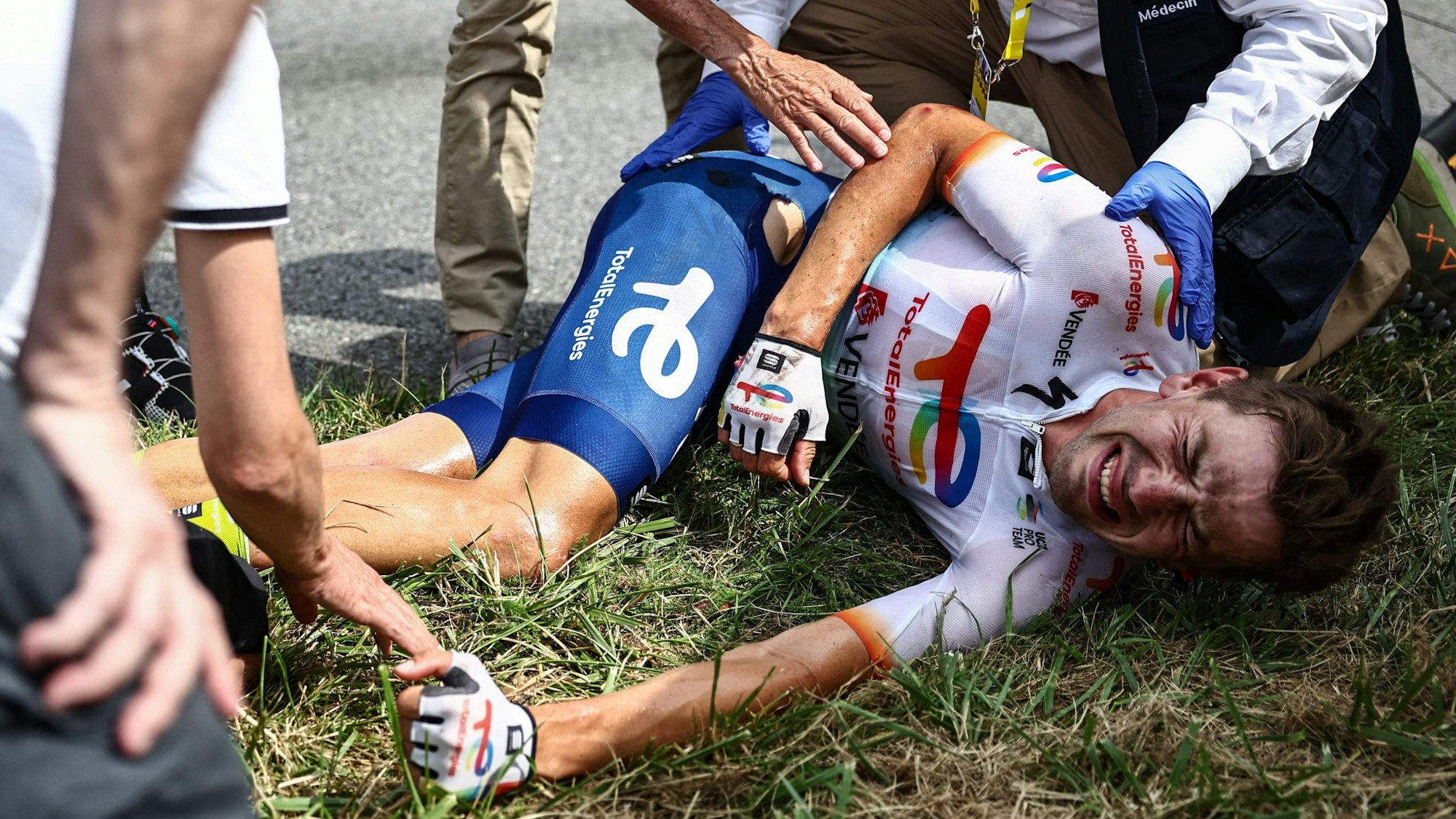 Steff Cras (M) aus Belgien vom Team TotalEnergies reagiert nach seinem Sturz auf der Strecke mit schmerzverzerrtem Gesicht