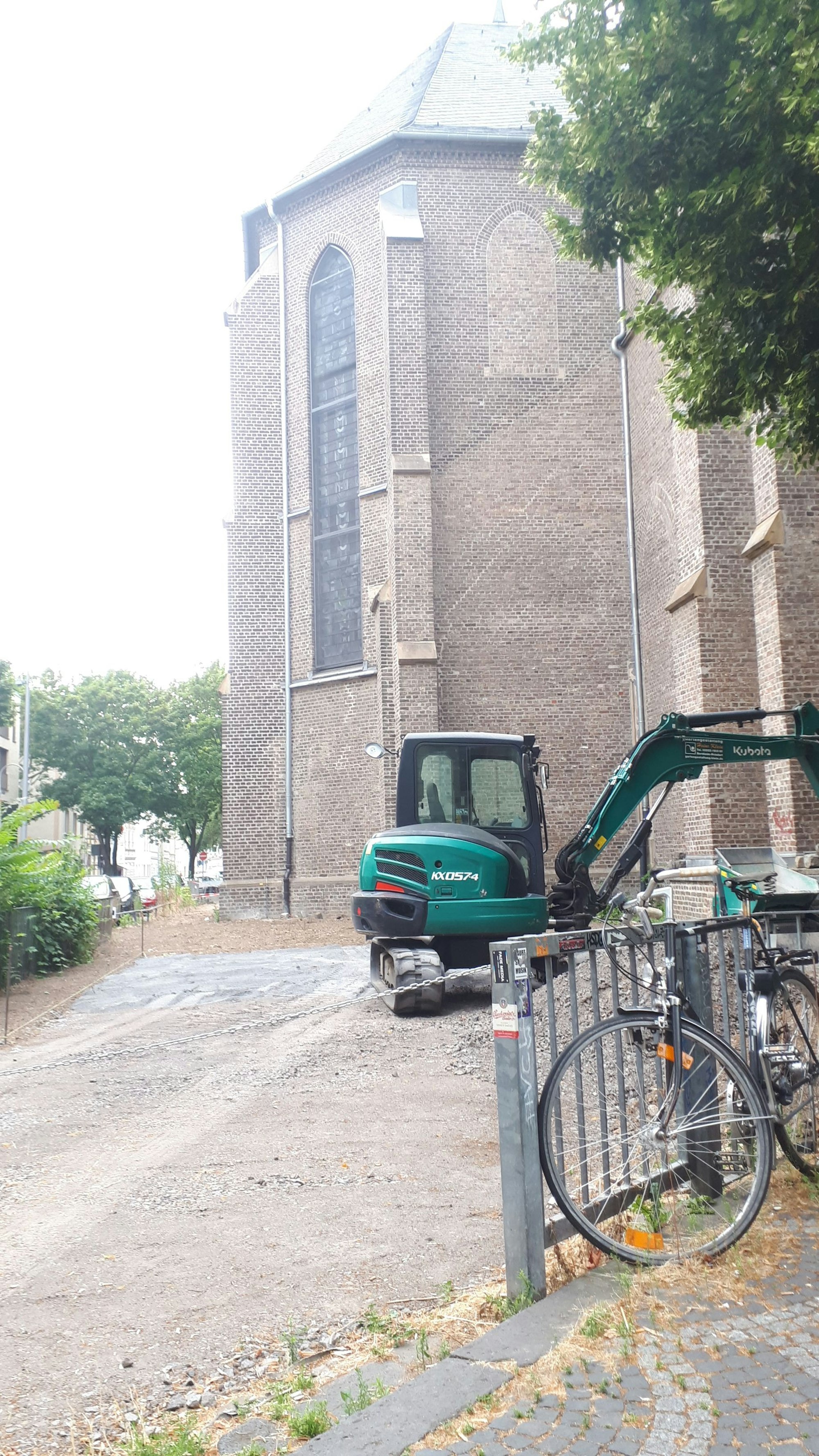 Vor der Kirche steht ein Bagger auf einer abgesperrten Baustelle.