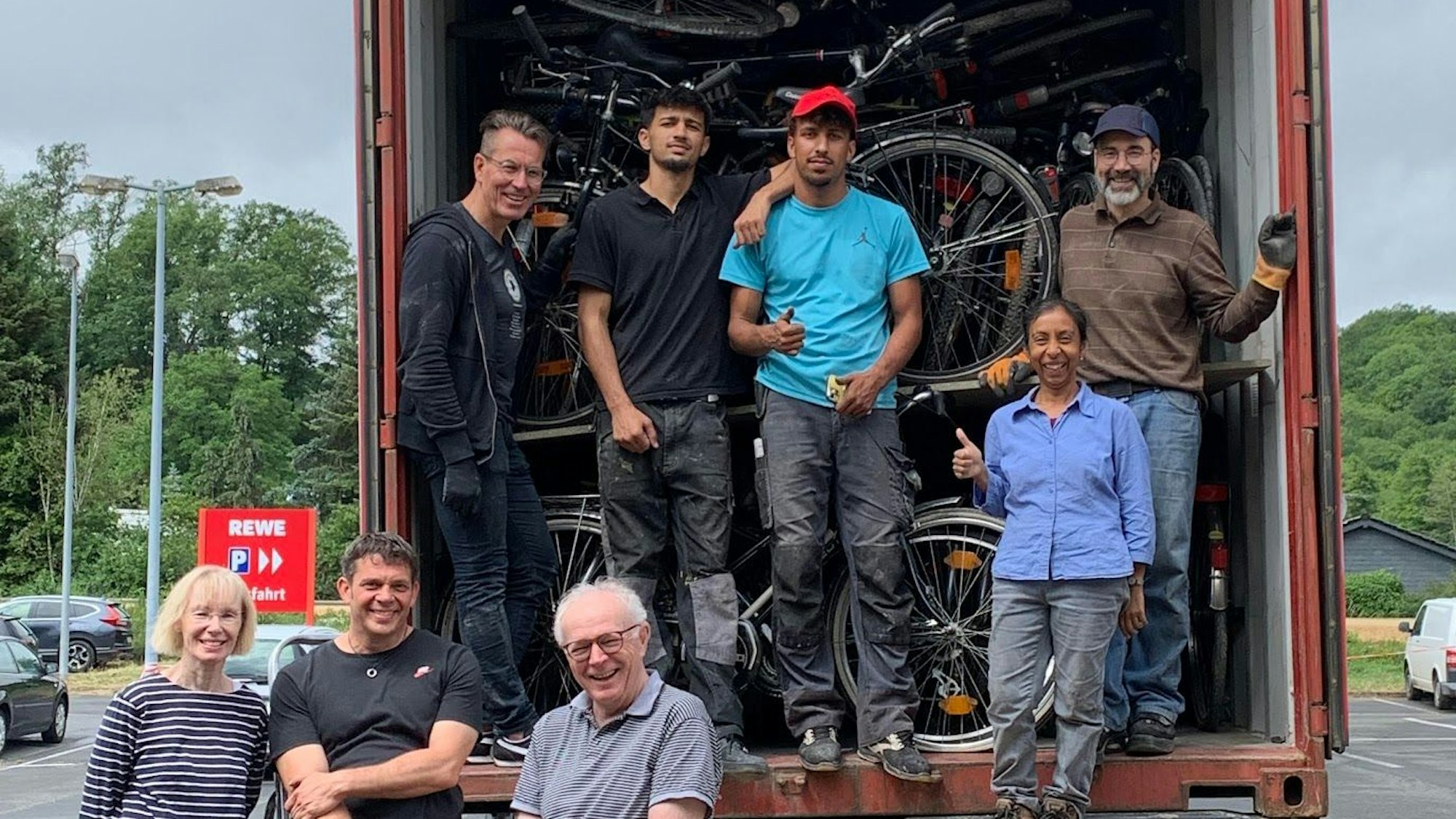 Eine Gruppe von Menschen steht vor einem mit Fahrrädern voll beladenem Container.