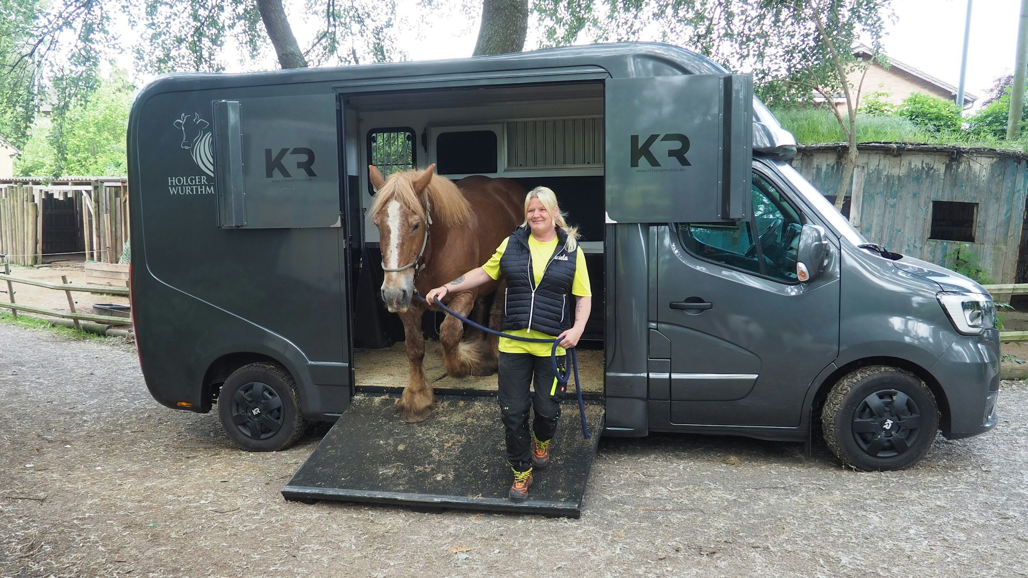 Daniela Schmitz führt ein Pferd am Halfter aus dem grauen Pferdetaxi.