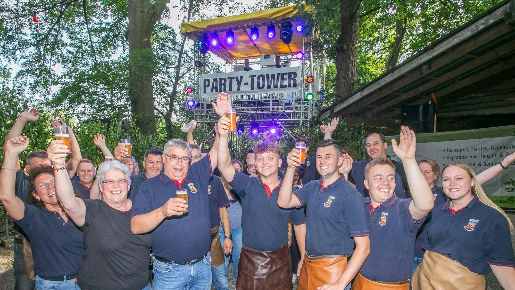 Mitglieder des Löschzugs Dörspetal der Bergneustädter Feuerwehr feiern ausgelassen unter dem Party-Tower. Und der steht mitten im Wald bei Pustenbach.