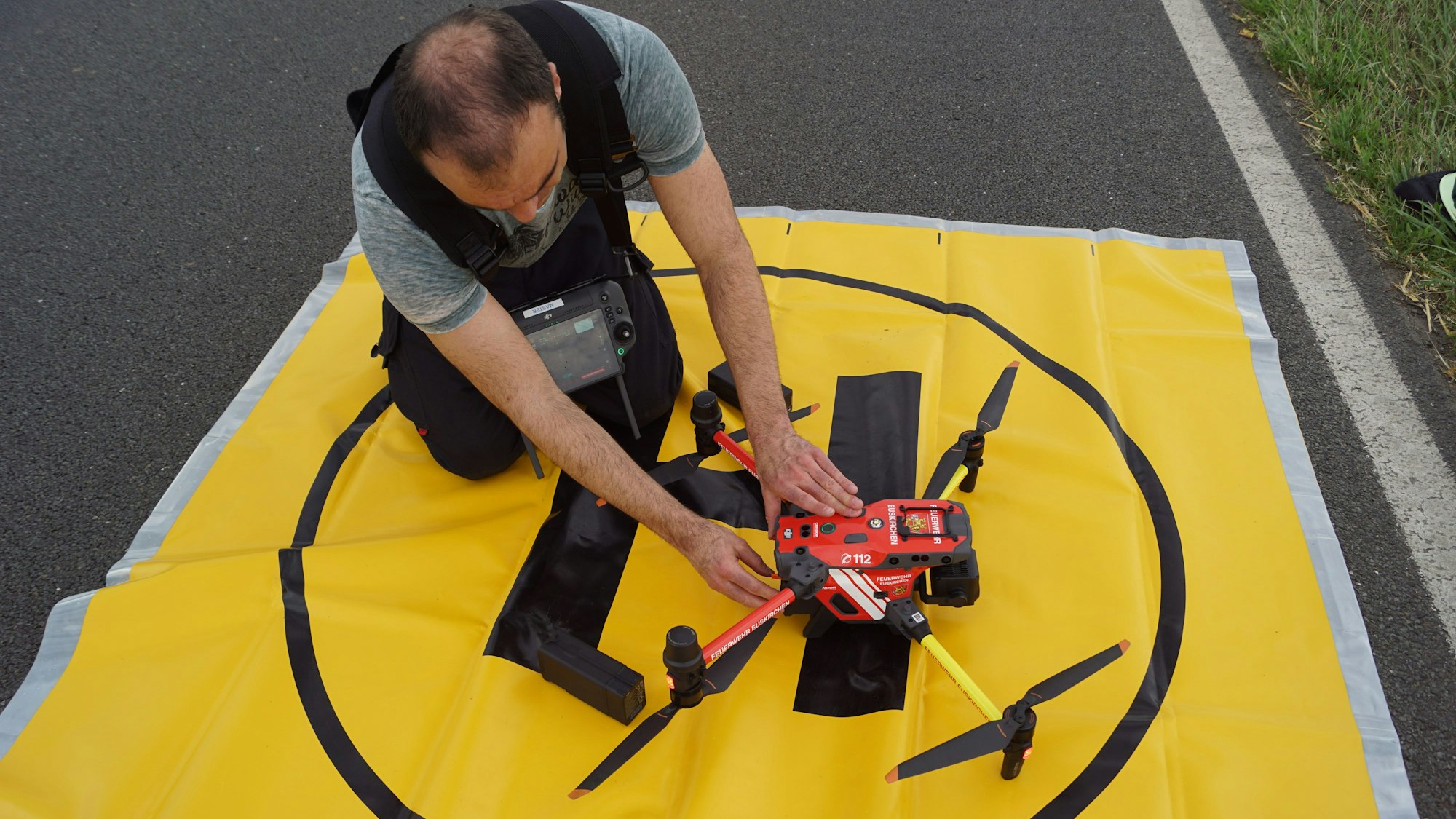 Der Pilot der Feuerwehr macht die Drohne auf ihrem Startplatz, der durch eine gelbe Folie markiert ist, startklar.