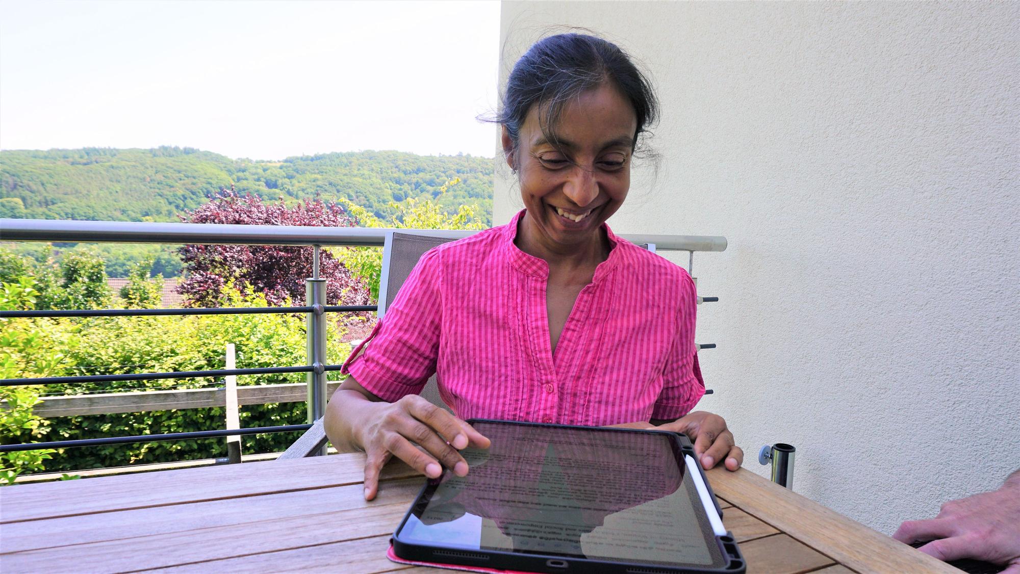 Kalika Wagner-Gillen sitzt auf ihrer Terrasse und bedient ein Tablet.